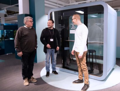 People conversing in front of a Framery Q meeting pod at an exhibition