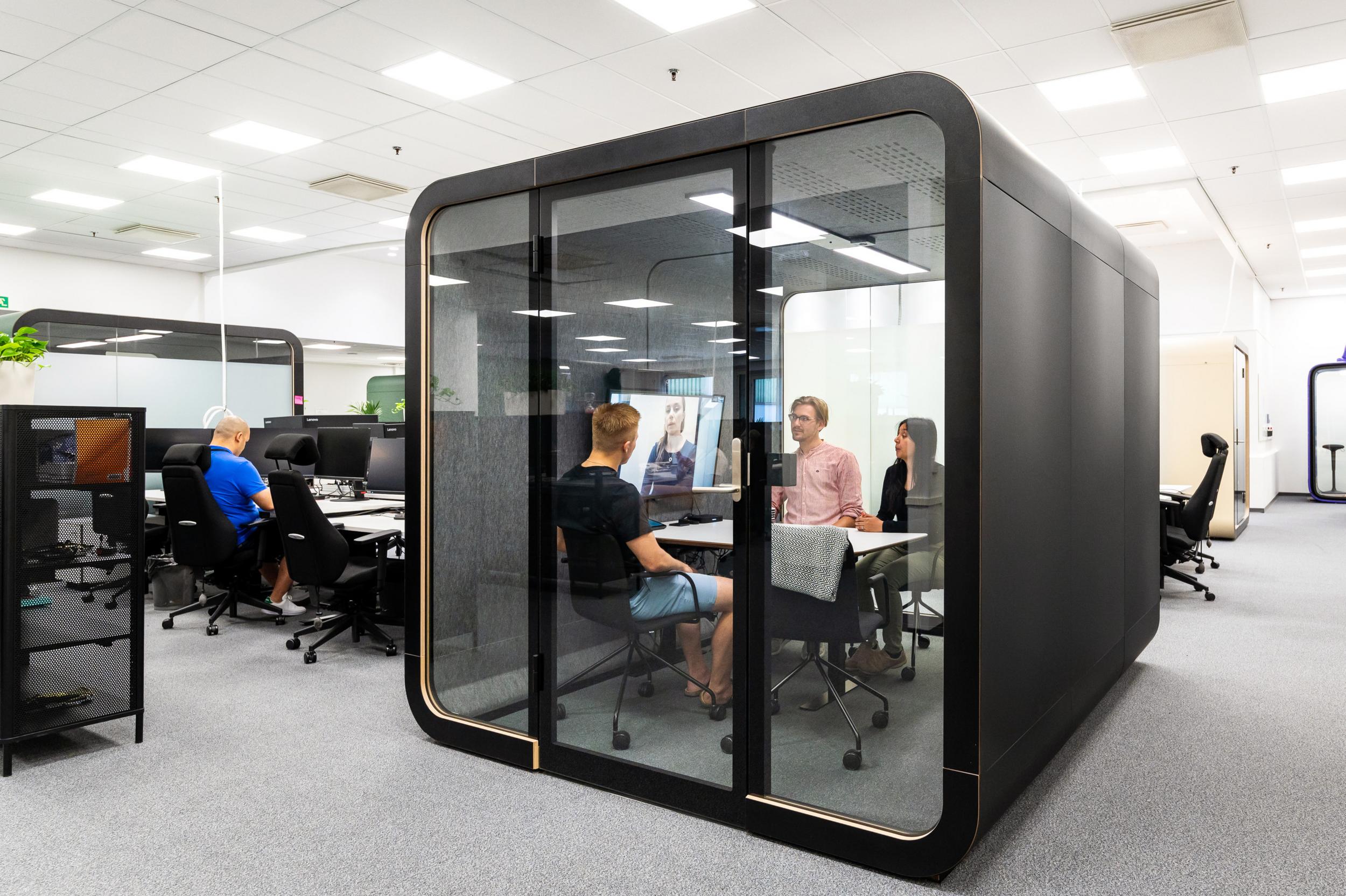 People having a meeting in a Framery 2Q Huddle office pod with Black exterior.
