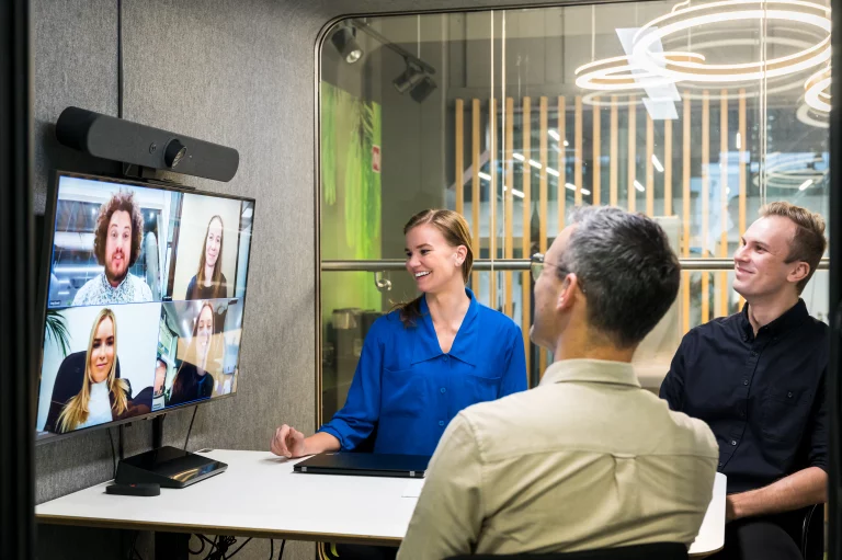 People having a hybrid meeting in a Framery 2Q Huddle using a Logitech video conferencing setup.