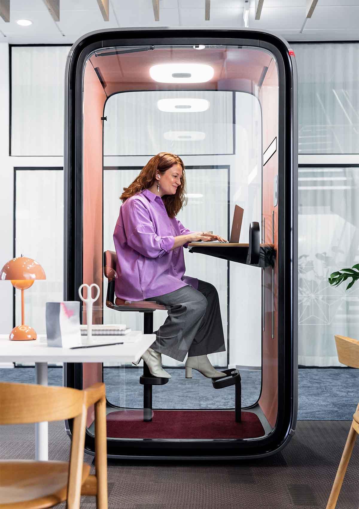 Woman working in Framery One utilizing its video conferencing light.