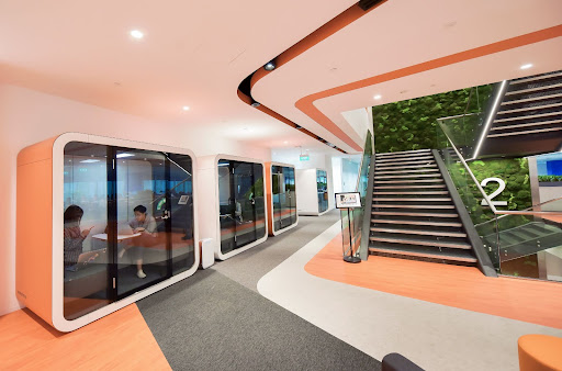 People working inside multiple Framery Q meeting pods in a corridor of an office building.