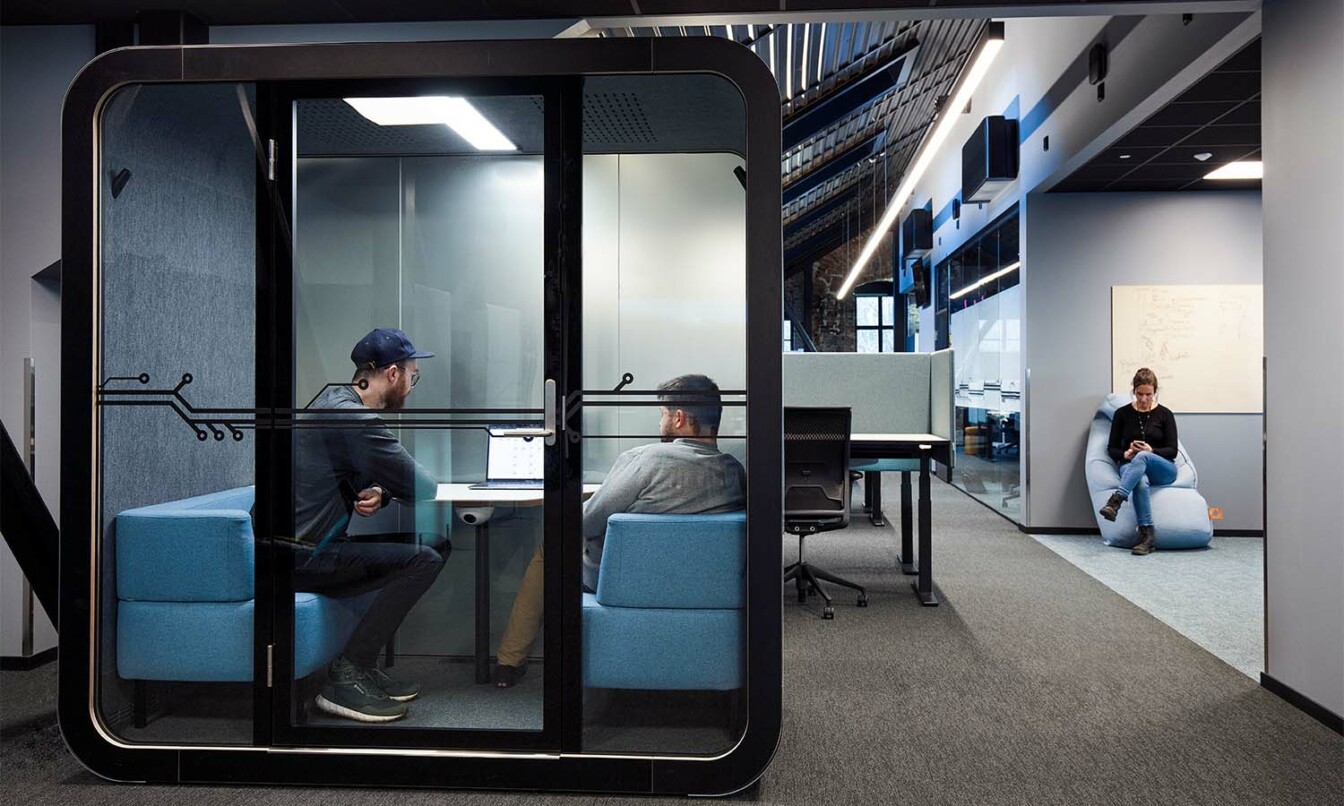 People having a meeting in a Framery soundproof pod while another person is having a break next to it.