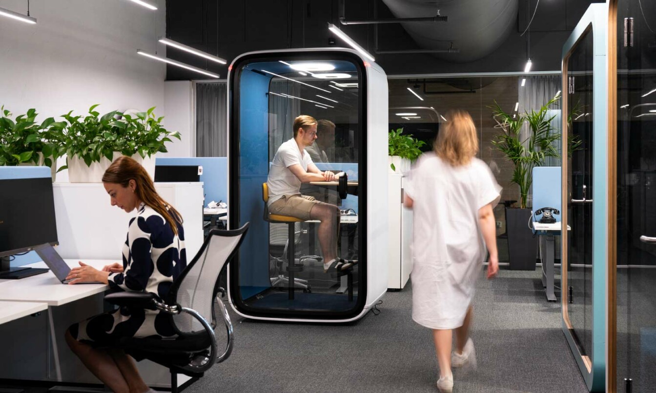 People using Framery One soundproof office pod in open-plan office